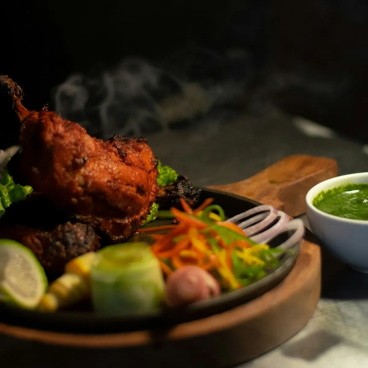 Tandoori chicken with smoke rising, served with green chutney and salad