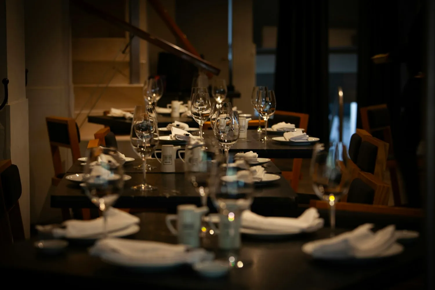 A dining room set for dinner, glasses and folded napkins in low, warm light