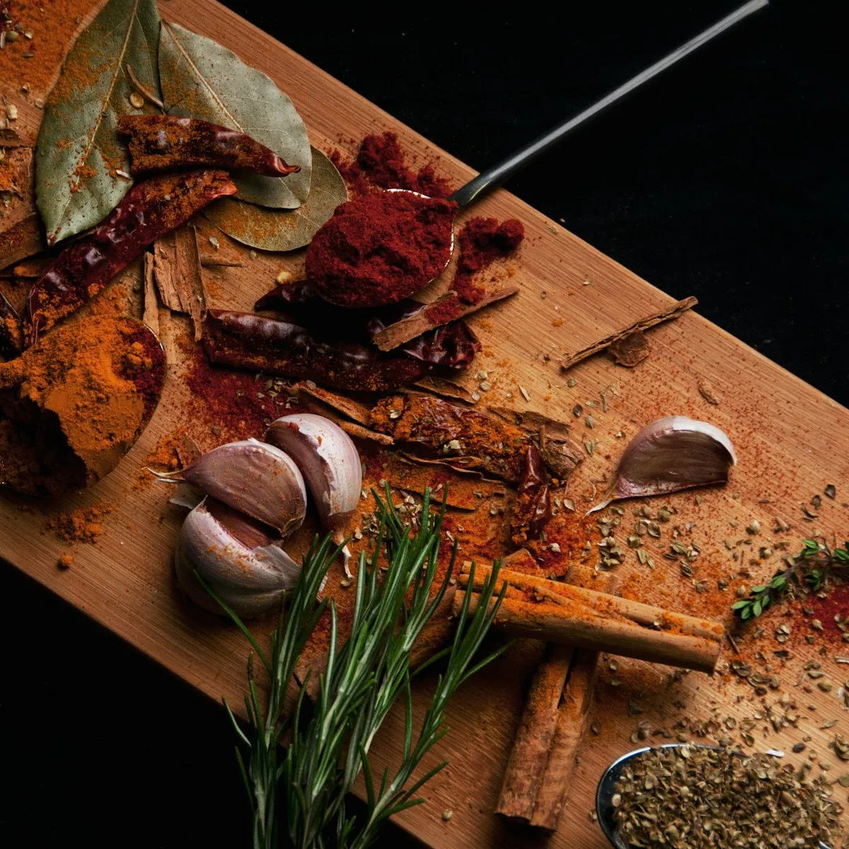 Dried chillies, garlic, cinnamon and ground spices on a wooden board