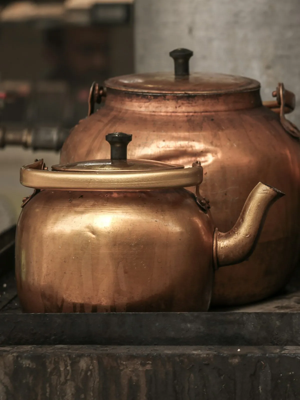Two copper kettles on an old stove, softly lit from the side