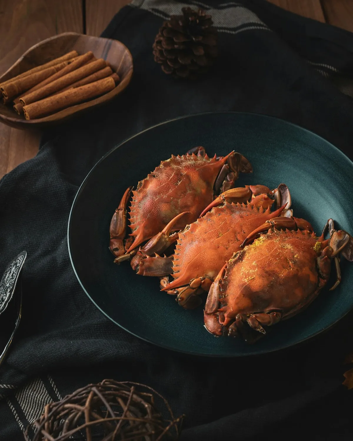 Three whole crabs on a dark green plate